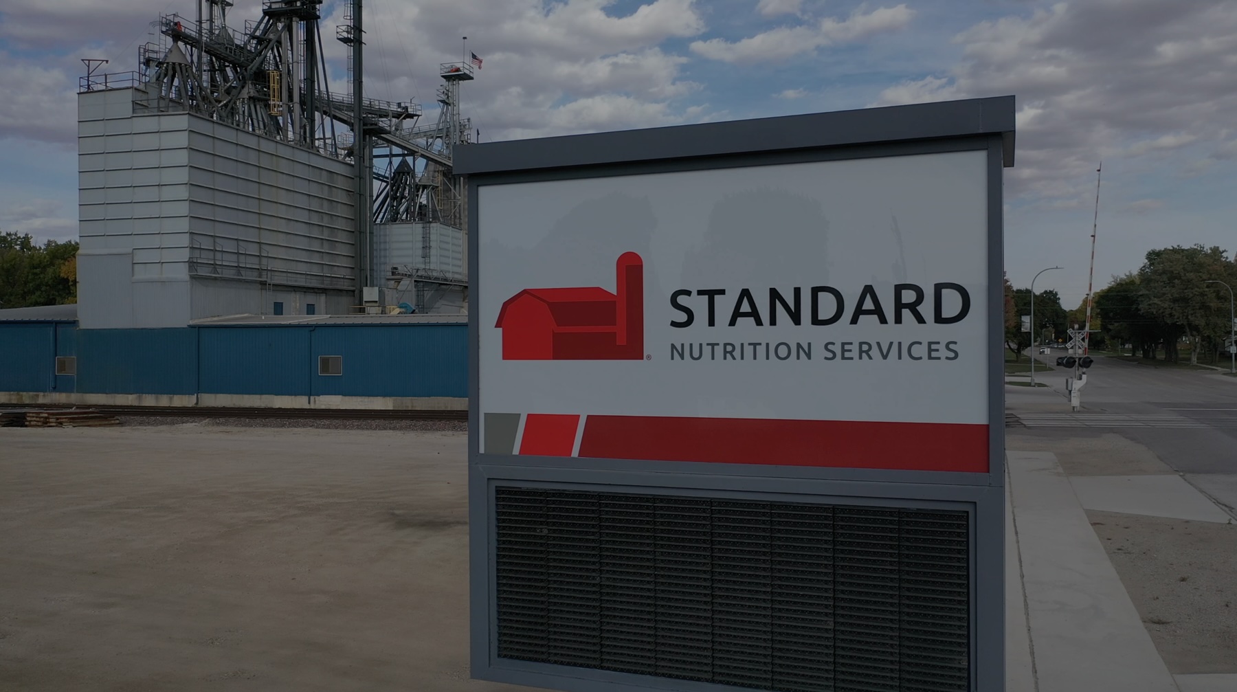 Signboard of Standard Nutrition Services with a red barn logo in front of an agricultural facility.